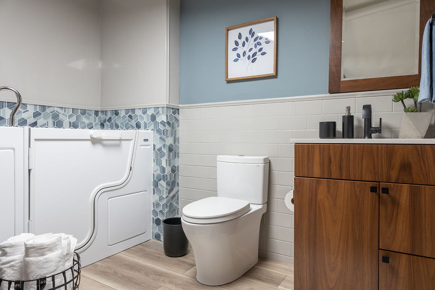 A remodeled bathroom showing a white toilet with a brushed nickel grab bar mounted on the adjacent wall, integrated into a stylish neutral-toned bathroom design.