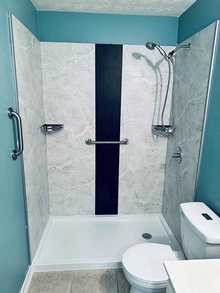 A walk-in shower with a brushed stainless steel grab bar installed on the tile wall, demonstrating a home modification for aging-in-place bathroom safety.