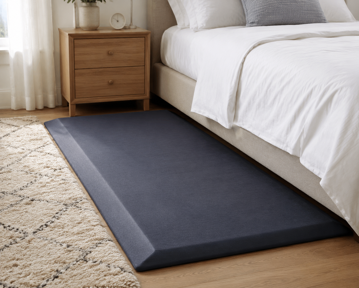 Thick gray bedside fall mat with beveled edge placed alongside a bed
