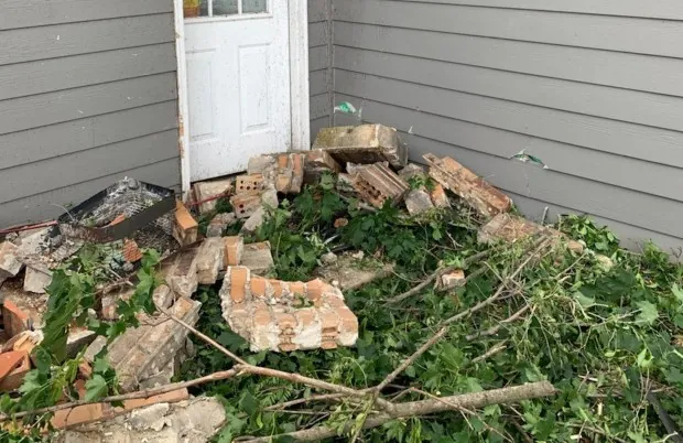 Close-up of grass with metal shards, broken plastic, and glass embedded after a tornado