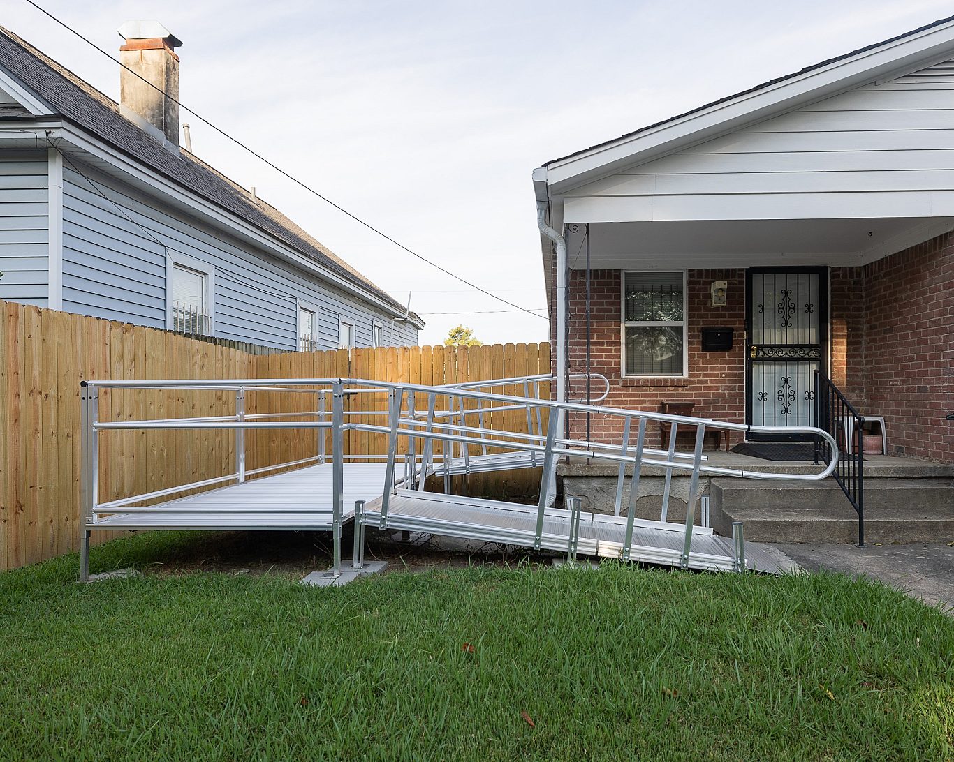 A wooden wheelchair ramp leading up to the front door of a house, built by Habitat for Humanity's Aging in Place program.