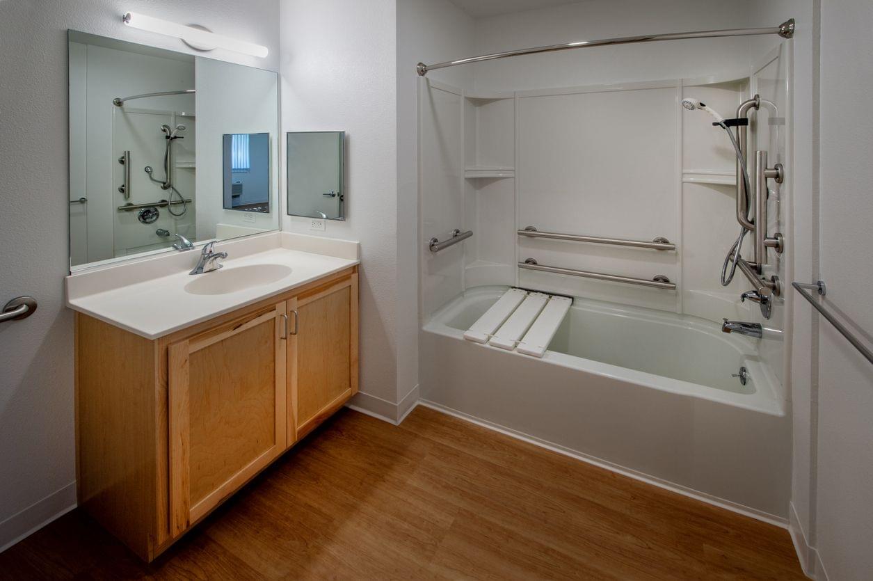 White transfer bench installed across a bathtub with legs inside and outside the tub