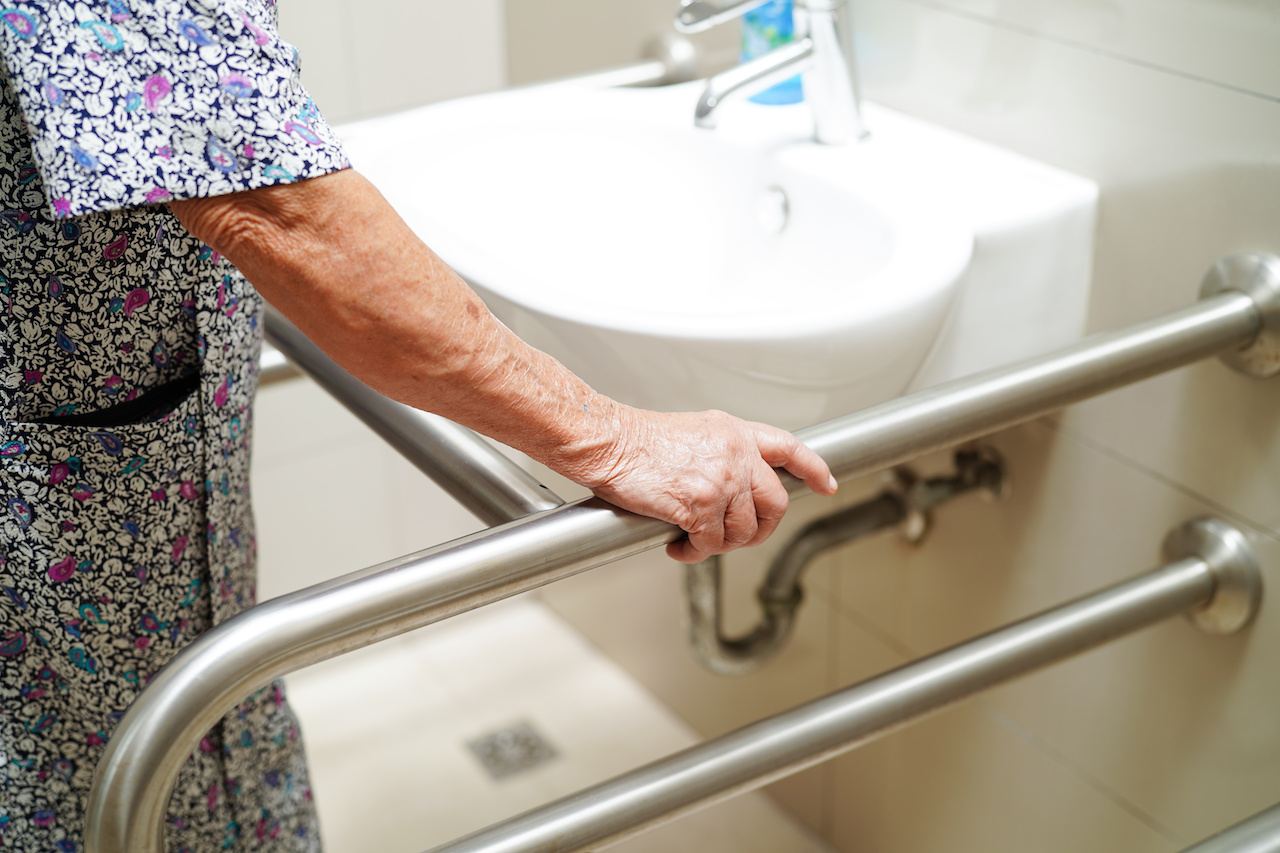 Older adult holding a bathroom grab bar near the sink
