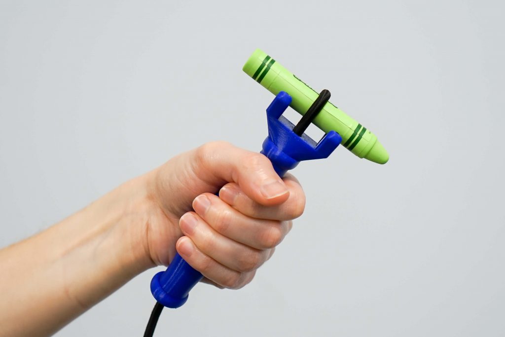 A hand wearing a silicone universal cuff holding an adaptive eating utensil