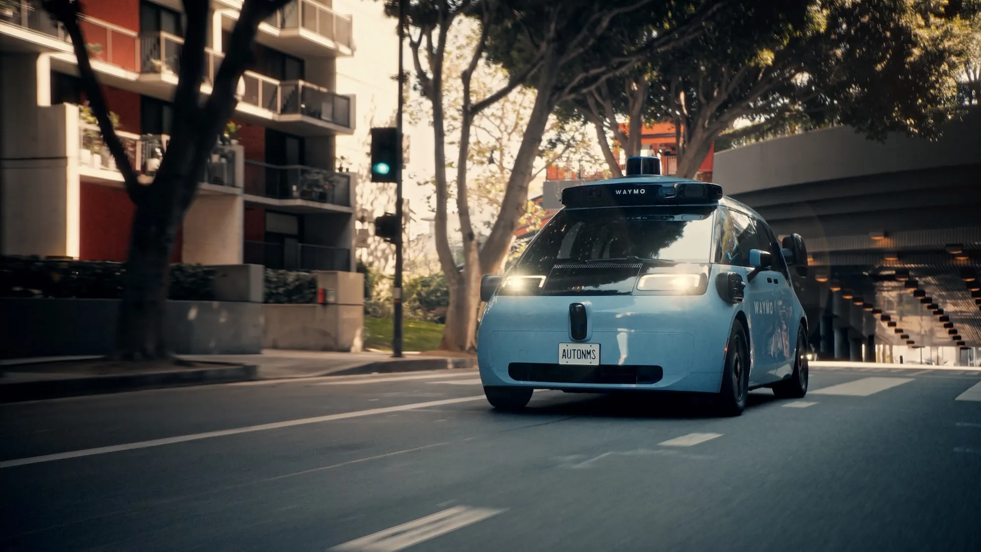 Waymo driverless robotaxi on a city street with rooftop sensors visible and no human driver behind the wheel