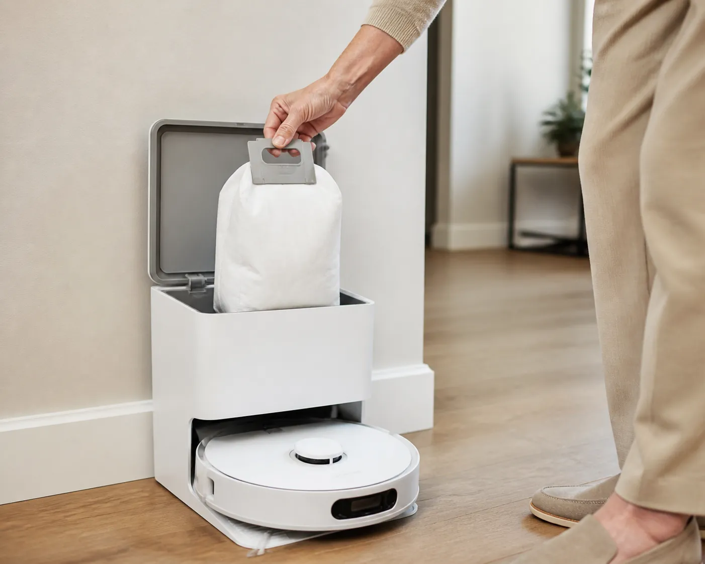 Self-emptying robot vacuum dock with a sealed dust bag being lifted by an older adult