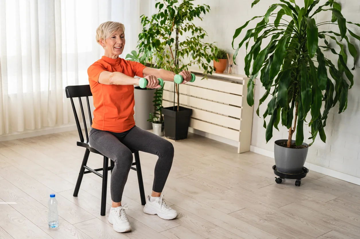 Senior woman performing a seated strengthening exercise at home