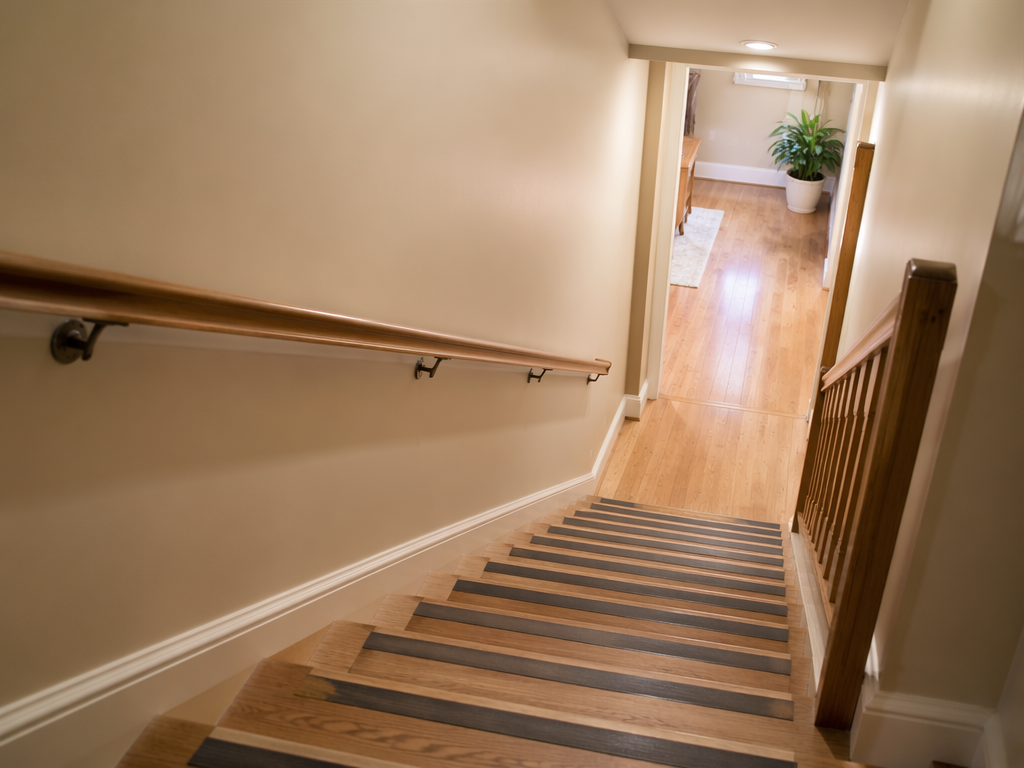 Residential staircase with handrail, lighting, non-slip tread strips, and a clear landing