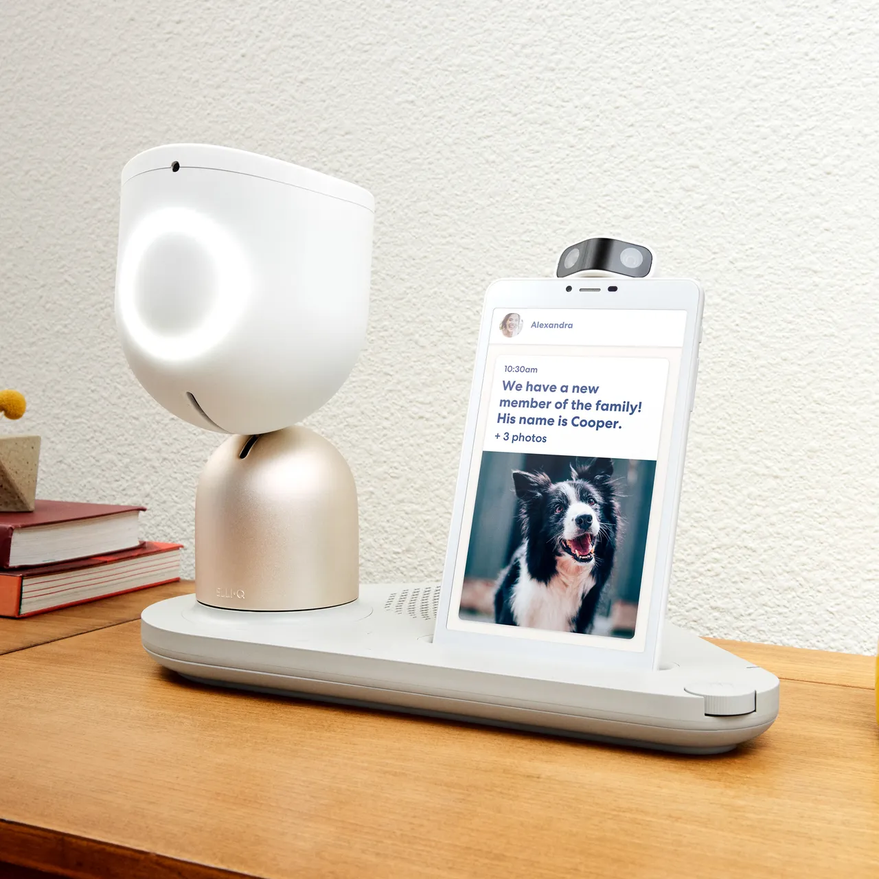 Older woman seated at a table with the ElliQ companion robot in a home kitchen