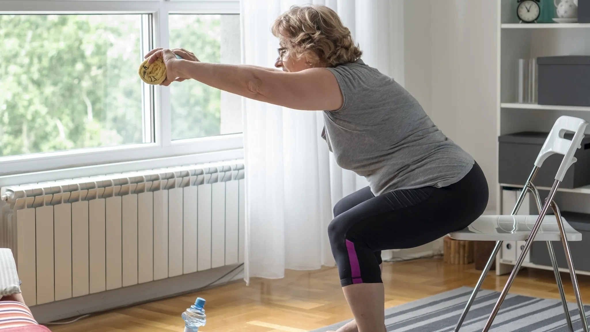 Older adult performing a sit-to-stand exercise from a sturdy chair at home