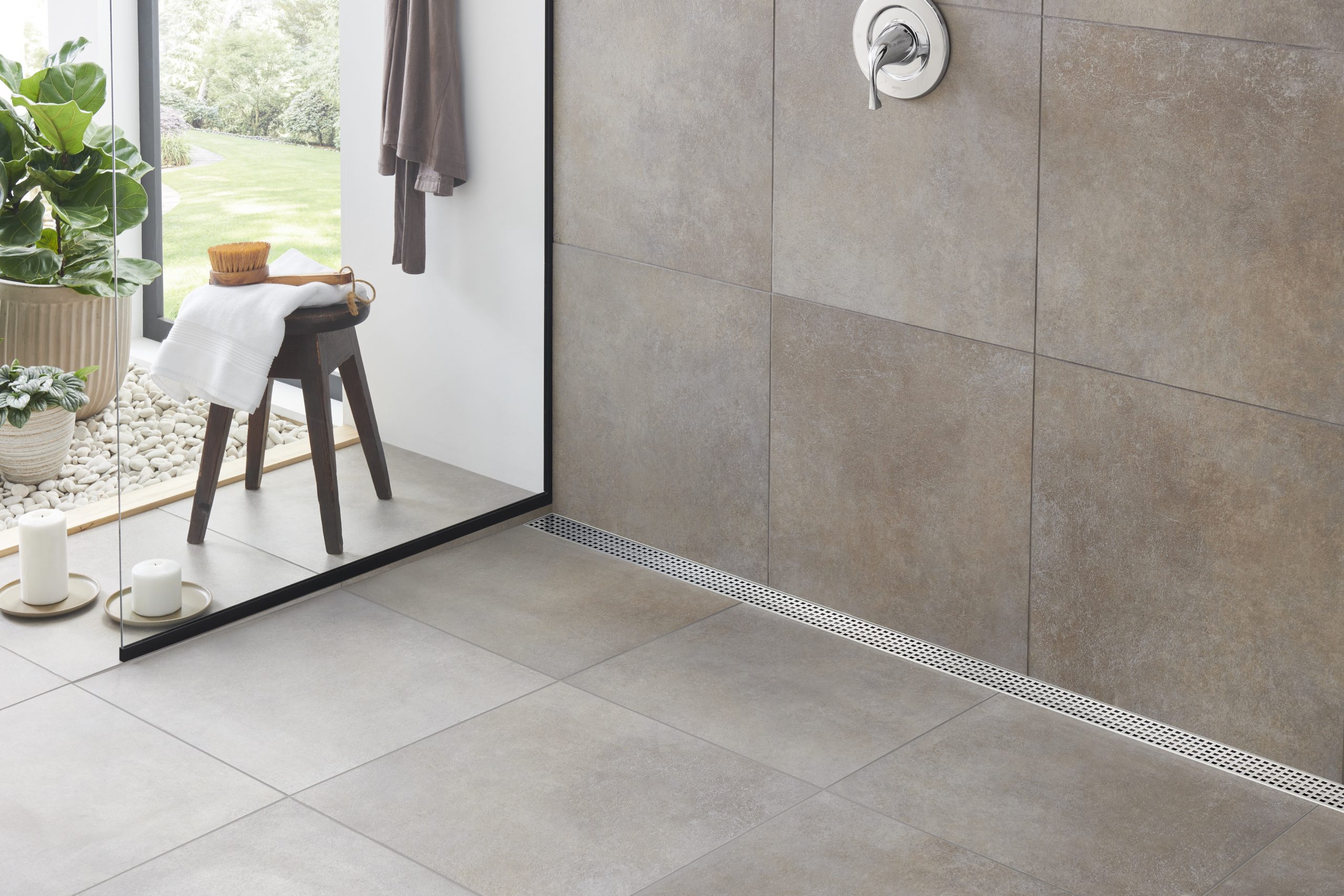 Curbless walk-in shower with a linear drain, white tile, wall niche, and glass enclosure