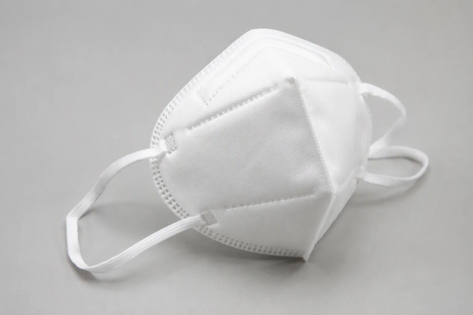 White NIOSH-approved N95 respirator on a light gray surface