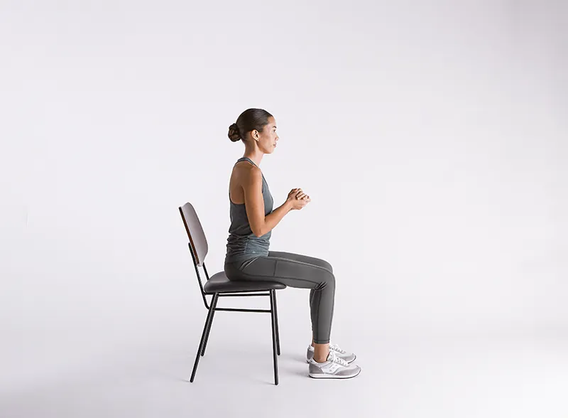 Woman performing a sit-to-stand chair exercise
