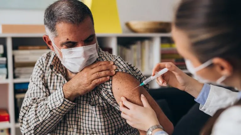 Older man receiving a flu vaccination from a healthcare professional
