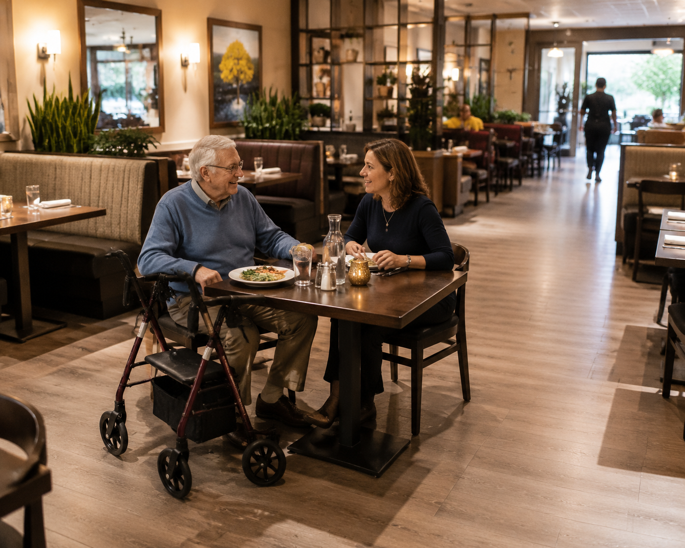 A middle-aged daughter and elderly father with a walker dining together in a spacious, warmly lit restaurant