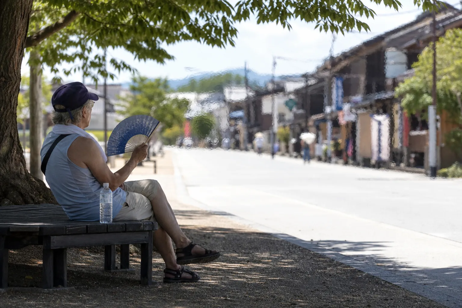 Older traveler resting on a shaded bench with a water bottle during a blazing Japanese summer midday
