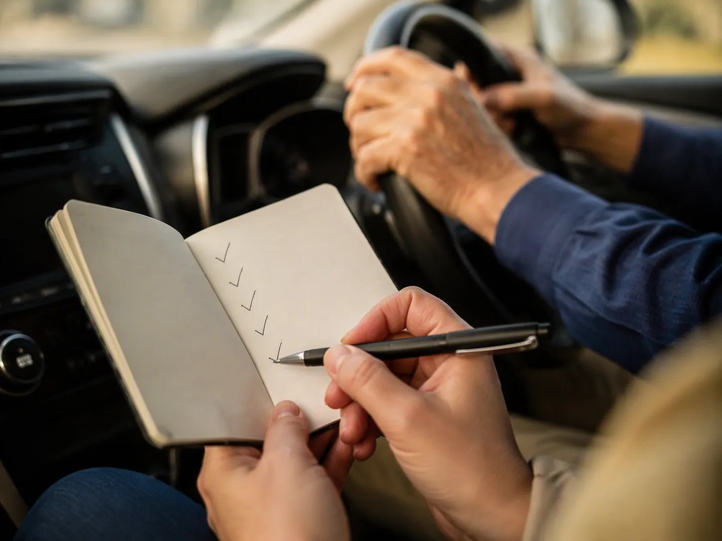 Passenger taking notes during an older parent's driving trip