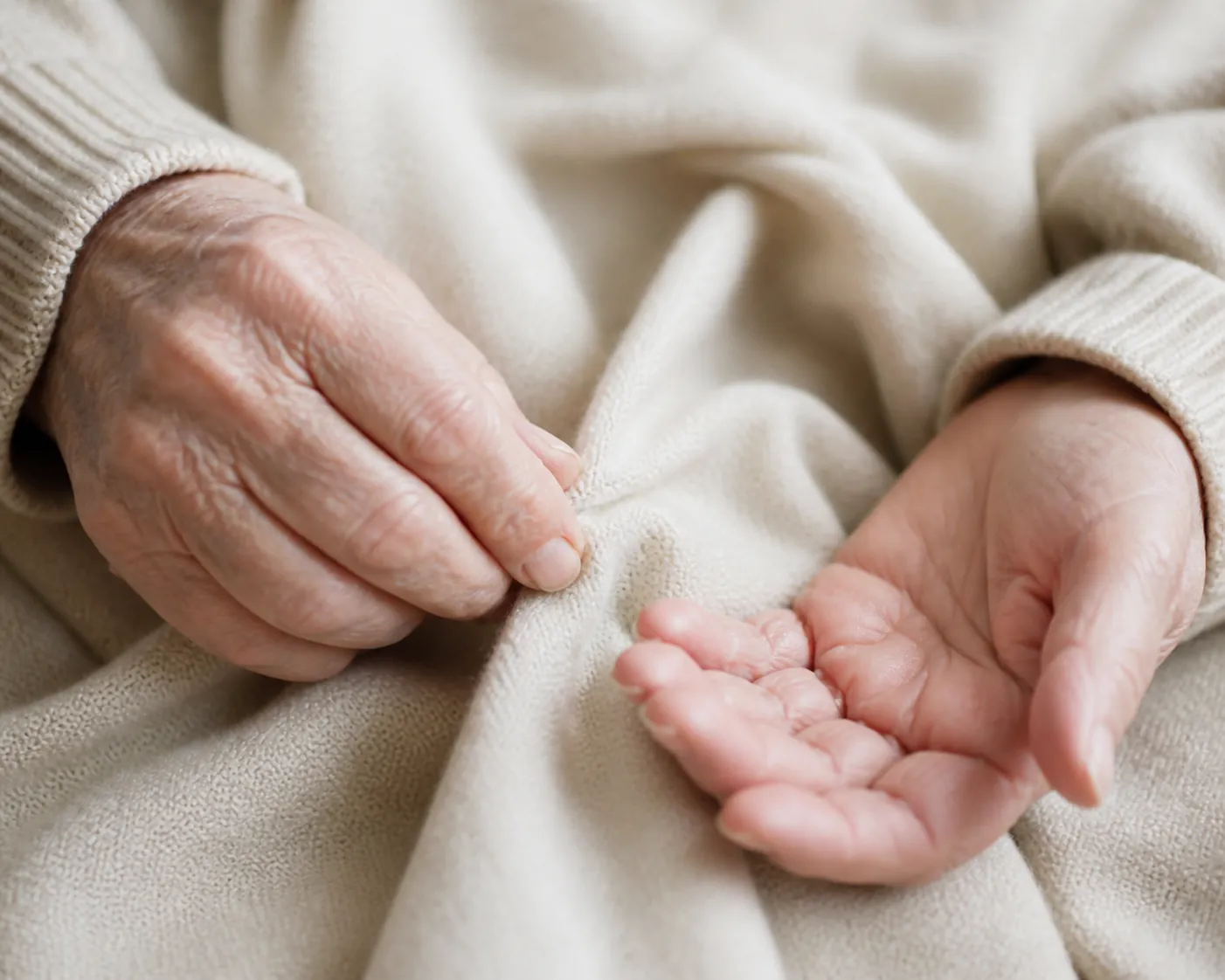 Elderly hands resting on a soft knit sweater with one hand feeling an inner seam